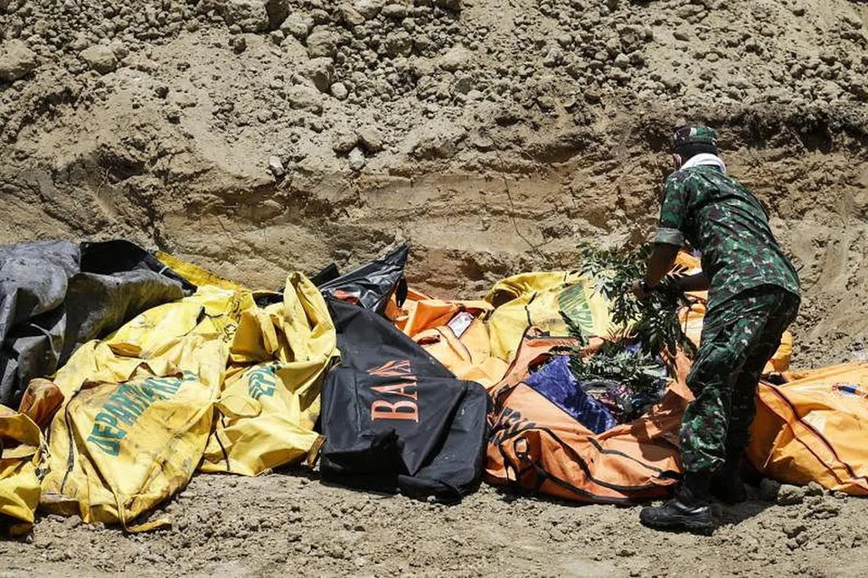 Seorang penyelamat menutup mayat mangsa bencana Indonesia semasa upacara pengebumian beramai-ramai di Palu. Foto: EPA 