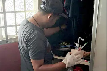 OPERASI MENYELURUH: Seorang pegawai CNB memeriksa sebuah unit semasa operasi serata Singapura dijalankan CNB dari pagi Isnin lalu hinggga semalam. - Foto CNB