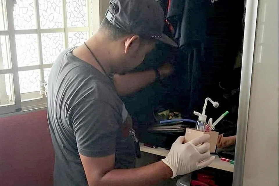 OPERASI MENYELURUH: Seorang pegawai CNB memeriksa sebuah unit semasa operasi serata Singapura dijalankan CNB dari pagi Isnin lalu hinggga semalam. - Foto CNB