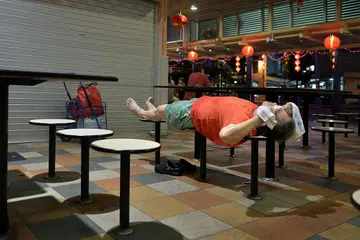 Seorang penjaja tidur selepas penat bekerja di gerainya di sebuah pusat penjaja. 