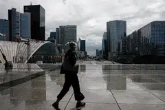 PAKAI PELITUP: Seorang penduduk sedang berjalan di distrik kewangan dan perniagaan di Paris sedang negara itu menimbangkan peraturan mahu mewajibkan pemakaian pelitup di lebih banyak tempat kerja. - Foto REUTERS