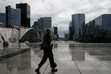 PAKAI PELITUP: Seorang penduduk sedang berjalan di distrik kewangan dan perniagaan di Paris sedang negara itu menimbangkan peraturan mahu mewajibkan pemakaian pelitup di lebih banyak tempat kerja. - Foto REUTERS