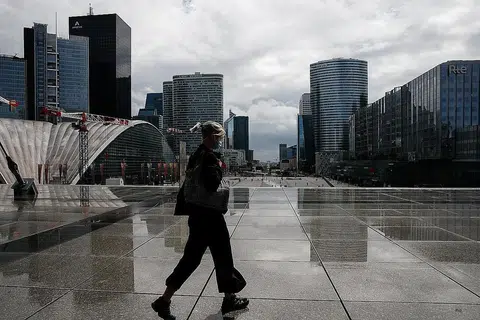 PAKAI PELITUP: Seorang penduduk sedang berjalan di distrik kewangan dan perniagaan di Paris sedang negara itu menimbangkan peraturan mahu mewajibkan pemakaian pelitup di lebih banyak tempat kerja. - Foto REUTERS