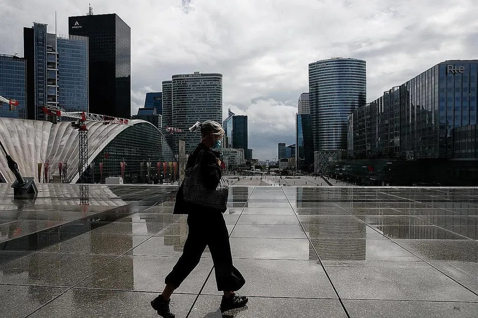 PAKAI PELITUP: Seorang penduduk sedang berjalan di distrik kewangan dan perniagaan di Paris sedang negara itu menimbangkan peraturan mahu mewajibkan pemakaian pelitup di lebih banyak tempat kerja. - Foto REUTERS