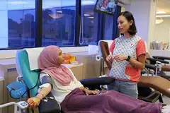 DERMA DARAH BUAT PERTAMA KALI: Wartawan ketika menderma darah buat kali pertama di Bank Darah di HSA. Bersamanya ialah Cik Candace Zhou, pengurus kanan Program Pengambilan Penderma Darah Palang Merah Singapura. - Foto SITI AISYAH NORDIN