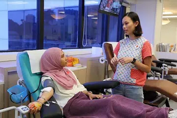 DERMA DARAH BUAT PERTAMA KALI: Wartawan ketika menderma darah buat kali pertama di Bank Darah di HSA. Bersamanya ialah Cik Candace Zhou, pengurus kanan Program Pengambilan Penderma Darah Palang Merah Singapura. - Foto SITI AISYAH NORDIN