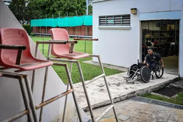 GIGIH BERDIKARI: Pemain ragbi kerusi roda, Aidil Khalip, yang juga pengurus pasukan dan naib presiden Persatuan Ragbi Kerusi Roda Singapura (WRAS), mengeluarkan kerusi roda dari bilik simpanan peralatan sebelum latihan di Pusat Sukan Toa Payoh pada 5 Julai. 
