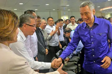 BERINTERAKSI: PM Lee bersalaman dengan pemimpin gerakan buruh semasa sesi dialog tertutup bersama mereka semalam. - Foto KHALID BABA