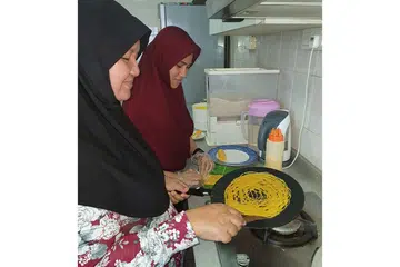 TERIMA SAMBUTAN BAIK: Lauk-pauk Raya oleh Tasty J Cuisine dimasak oleh ibu Encik Ismail Hashim, Cik Jainab Mohamad (kiri) dan isterinya Rahmawati (kanan). Encik Ismail turut membantu memasak. - Foto TASTY J CUISINE