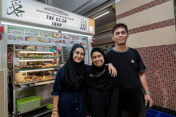 INGIN BANTU GOLONGAN MEMERLUKAN: Cik Hani Isnin bersama ibu bapanya Cik Munah dan Encik Isnin di depan gerai mereka yang terletak di Pusat Makanan Jalan Kukoh. - Foto-foto BM oleh NUR DIYANA TAHA