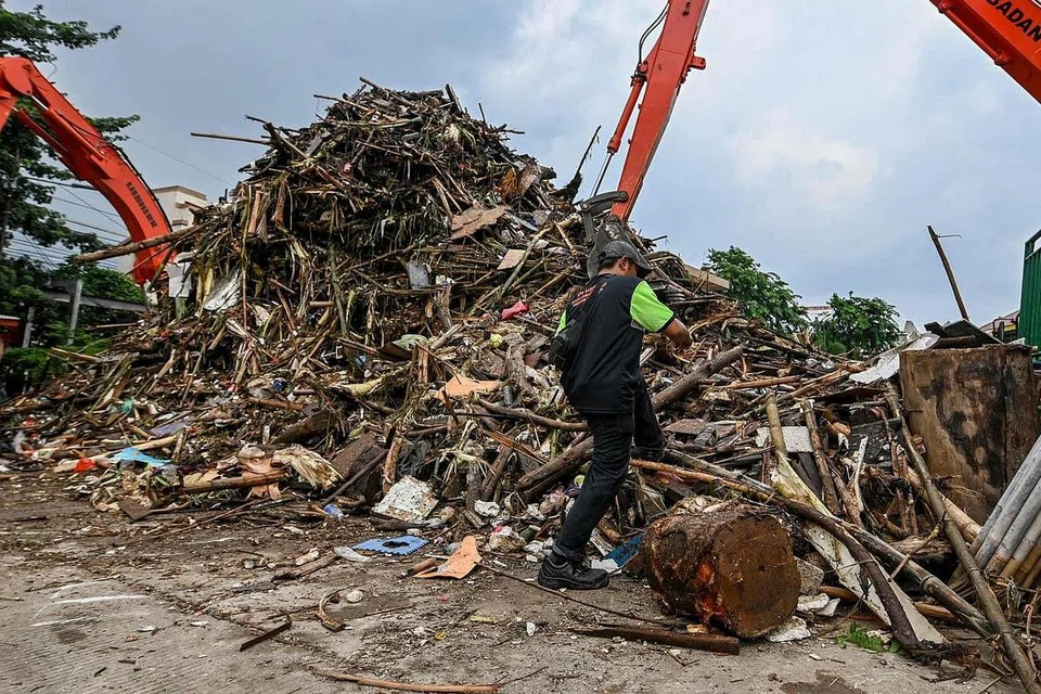 BANYAK SAMPAH: Seorang pekerja kelihatan sedang membersihkan sampah dan serpihan pokok di tepi sebuah sungai di Jakarta, selepas berlakunya banjir besar di ibu kota itu pada awal tahun baru lalu. - Foto AFP