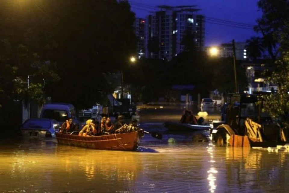BANJIR KILAT: Pegawai penyelamat membantu beberapa penduduk yang terperangkap untuk keluar dari rumah mereka di Jalan P. Ramlee di Georgetown, Pulau Pinang.