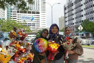 JUAL SEMPENA KONVOKESYEN: (Dari kiri) Cik Noraini, Cik Qaseh Maria dan Cik Azlina merupakan antara peniaga bunga yang berjualan di sepanjang jalan menuju ke Universiti Pengurusan dan Sains Malaysia (MSU) di Seksyen 13, Shah Alam. 