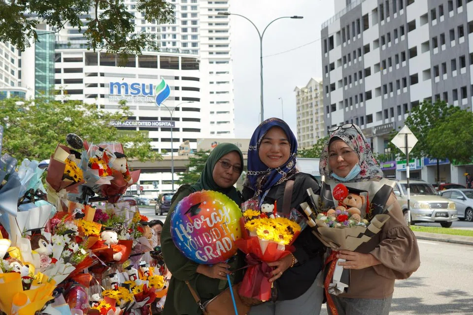 JUAL SEMPENA KONVOKESYEN: (Dari kiri) Cik Noraini, Cik Qaseh Maria dan Cik Azlina merupakan antara peniaga bunga yang berjualan di sepanjang jalan menuju ke Universiti Pengurusan dan Sains Malaysia (MSU) di Seksyen 13, Shah Alam. 
