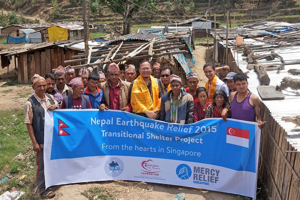 TEMPAT BERTEDUH SEMENTARA: Encik Herman (berbaju oren) bergambar di tapak tempat tinggal sementara mangsa gempa bumi yang dibina di Nepal. - Foto-foto MUIS 