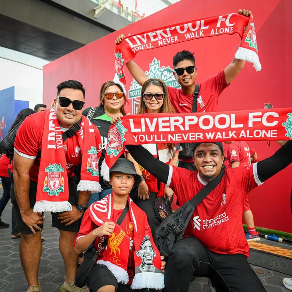 BERSEMANGAT: Peminat Liverpool Encik Muhamad Sufian Salim, 38 tahun (paling kiri), dan Encik Muhammad Asri Ibrahim, 37 tahun (paling kiri, melutut), bersama rakan penyokong lain teruja menonton perlawanan The Reds menentang Bayern Munich di Stadium Negara pada Rabu. 