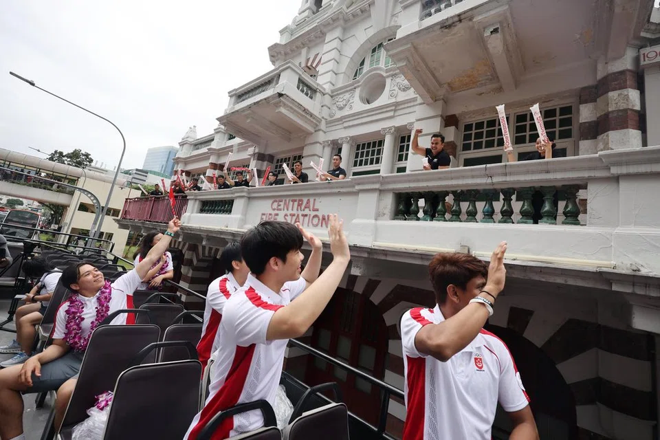 Atlet luncur lelayang, Maximilian Maeder (empat dari kanan) bersama rakan-rakan Olimpik lain melambai kepada anggota Pasukan Pertahanan Awam Singapura (SCDF) semasa perarakan sambutan One Team Singapore yang melalui Balai Bomba Central pada 14 Ogos.