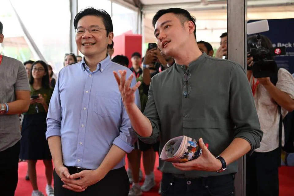 LIHAT PAMERAN: Timbalan Perdana Menteri Lawrence Wong (kiri) dan pengarah filem, Encik Boo Junfeng, menonton filem yang dipamerkan di Festival Melakar Hala Tuju Singapura di taman persisiran, Gardens by the Bay, pada 27 Oktober 2023.