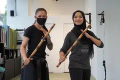 BAK SRIKANDI: Koresponden Shahida Sarhid (kanan) bersama pelatih, Cik Rose daripada Kali Majapahit bergambar dengan batang kayu yang diperbuat daripada rotan selepas sesi latihan. - Foto BH