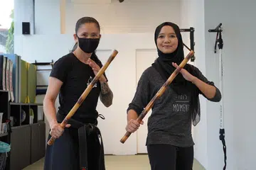BAK SRIKANDI: Koresponden Shahida Sarhid (kanan) bersama pelatih, Cik Rose daripada Kali Majapahit bergambar dengan batang kayu yang diperbuat daripada rotan selepas sesi latihan. - Foto BH