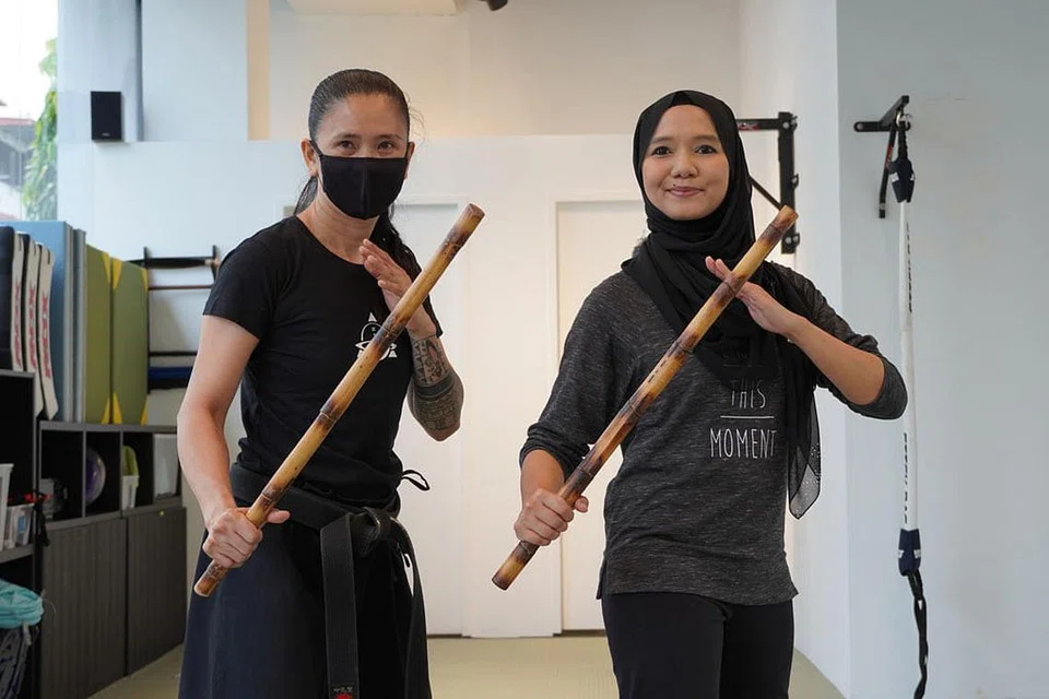 BAK SRIKANDI: Koresponden Shahida Sarhid (kanan) bersama pelatih, Cik Rose daripada Kali Majapahit bergambar dengan batang kayu yang diperbuat daripada rotan selepas sesi latihan. - Foto BH