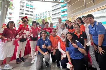 DEKATI PENDUDUK: Menteri Kedua Perdagangan dan Perusahaan, Dr Tan See Leng (di belakang, kanan, berbaju putih) dan Menteri Ehwal Luar, Dr Vivian Balakrishnan (di belakang, kiri, berbaju biru) bergambar bersama penduduk Marine Parade di Karnival Hari Kebangsaan Marine Parade pada Ahad.
