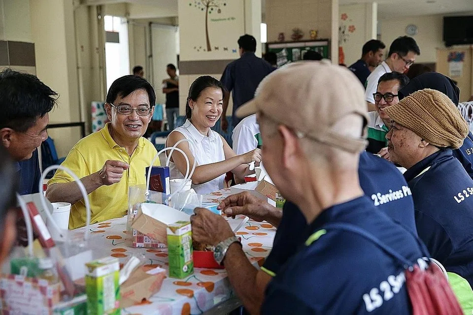 USAHA DIHARGAI: Encik Heng (dua dari kiri) dan Anggota Parlimen GRC Tampines, Cik Cheng Li Hui (tiga dari kiri) beramah mesra dengan pekerja pembersihan selepas pengagihan pek penjagaan kepada golongan itu di kolong Blok 842, Tampines Street 82, semalam. - Foto BH oleh KEVIN LIM