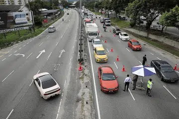 DIPERIKSA: Pemandu melalui sekatan jalan raya yang dilaksanakan di Kuala Lumpur. - Foto REUTERS 
