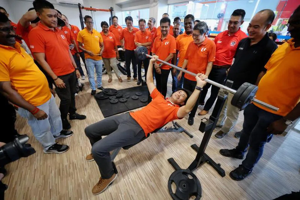 Timbalan Setiausaha Agung Kongres Kesatuan Sekerja Kebangsaan (NTUC), Encik Desmond Tan (tengah), mencuba mengangkat besi di gimnasium baru Kelab Rekreasi Pusat Pekerja Migran pada 23 Jun.