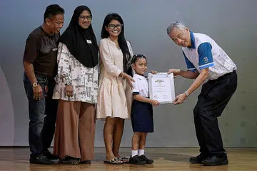 BANTU PENDIDIKAN: Mikayla Aulani, 8 tahun, menerima dermasiswa daripada Encik Lee sambil ditemani ibunya, Cik Baihirah Nurul Baihirah Hanim, 27 tahun, neneknya, Cik Sarimah Mohd, 55 tahun dan datuknya, Encik Abdul Aziz, 58 tahun. - Foto BM oleh NG SOR LUAN
