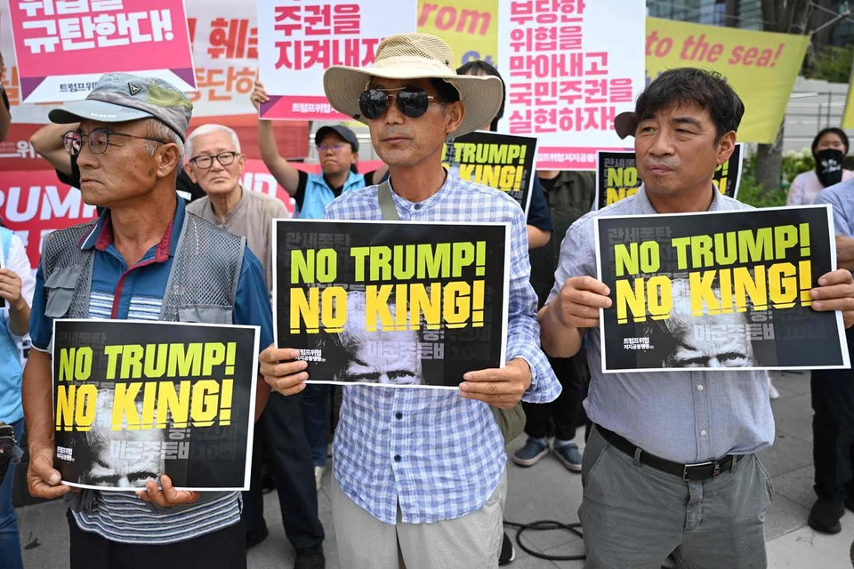 Penunjuk perasaan Korea Selatan memegang plakad bertulis “No Trump! No King!” ketika berhimpun membantah dasar tarif Presiden Amerika Syarikat, Donald Trump, berhampiran kedutaan Amerika di Seoul pada 31 Julai 2025. Presiden Trump pada 30 Julai berkata Amerika Syarikat akan mengenakan tarif sebanyak 15 peratus ke atas import dari Korea Selatan, sambil mempromosikan “perjanjian perdagangan penuh dan lengkap” antara kedua-dua negara. 