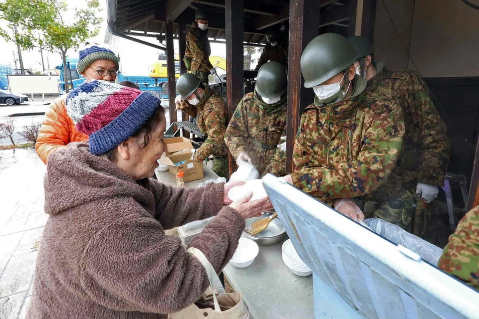 BANTUAN KERAJAAN: Seorang wanita tua menerima makanan yang diberikan oleh tentera Jepun (JSDF). Namun, cuaca sejuk dan salji menimbulkan cabaran untuk bahan bantuan sampai kepada mereka yang memerlukan.