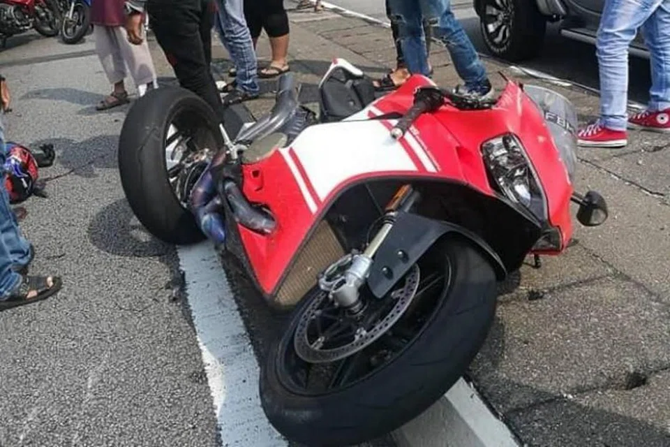 MAUT AKIBAT KEMALANGAN: Gambar yang tular di Facebook menunjukkan motosikal merah dan putih dengan plat nombor berdaftar Singapura di bahu jalan. Foto: FACEBOOK/HA NYUT