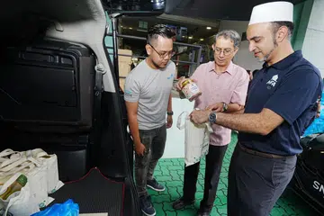 Menteri Negara (Ehwal Dalam Negeri merangkap Pembangunan Negara), Profesor Madya Dr Muhammad Faishal Ibrahim (tengah), dan CEO MTFA, Dr Abdul Qader Al-Aidaroos (kanan), menyusun habuan ‘Aidilfitri penuh Ihsan’ ke dalam kereta seorang relawan, Encik Muhammad Nashri Jupri, untuk dihantar kepada penerima. 