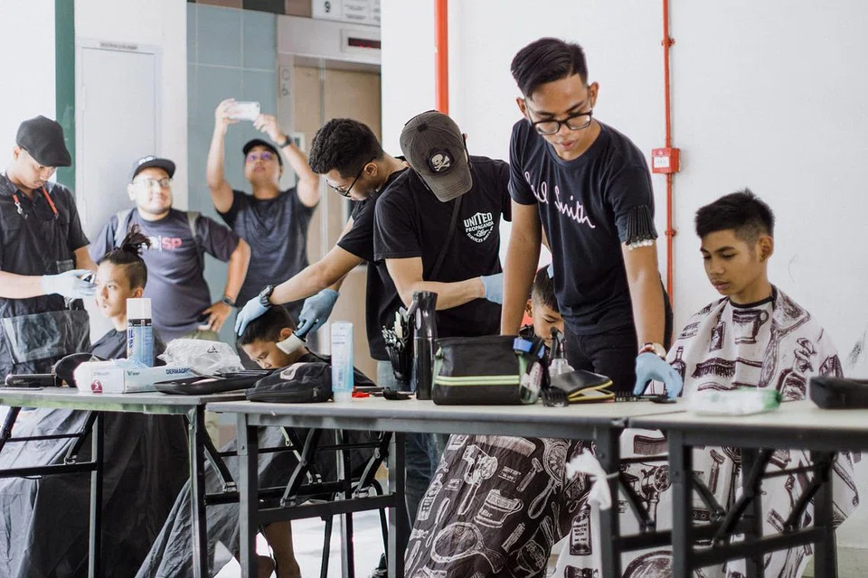 PERSIAPAN SEBELUM RAYA: Seramai tujuh tukang gunting rambut meluangkan masa menggunting rambut penduduk Jalan Kukoh, Jalan Minyak dan York Hill dalam acara amal bagi menyuntik keceriaan sebelum Lebaran pada 10 Jun lalu. - Foto MUHAMMAD ROSLI