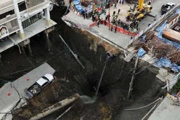Sebuah kenderaan kelihatan hampir terjatuh di tepi lubang benam besar yang terbuka di Jalan Samsen berhampiran Hospital Vajira, Bangkok, Thailand, 24 September 2025    