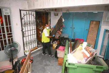 Seorang pekerja majlis bandaran mengalihkan barangan daripada sebuah unit flat lima bilik di Blok 971 Hougang Street 91 pada 10 Januari 2025, sehari selepas kebakaran berlaku di unit berkenaan yang mengakibatkan tiga maut.