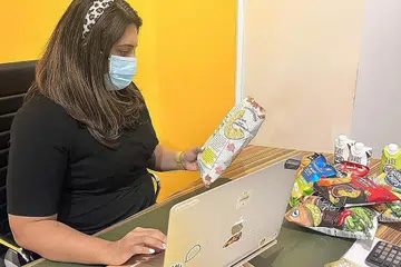 KERJA KERAS: Pengarah Asian Food Network Pte Ltd, Cik Anusha Aswani, sedang memuat naik maklumat terkini tentang kerepek baru syarikat mereka. - Foto-foto ASIAN FOOD NETWORK PTE LTD