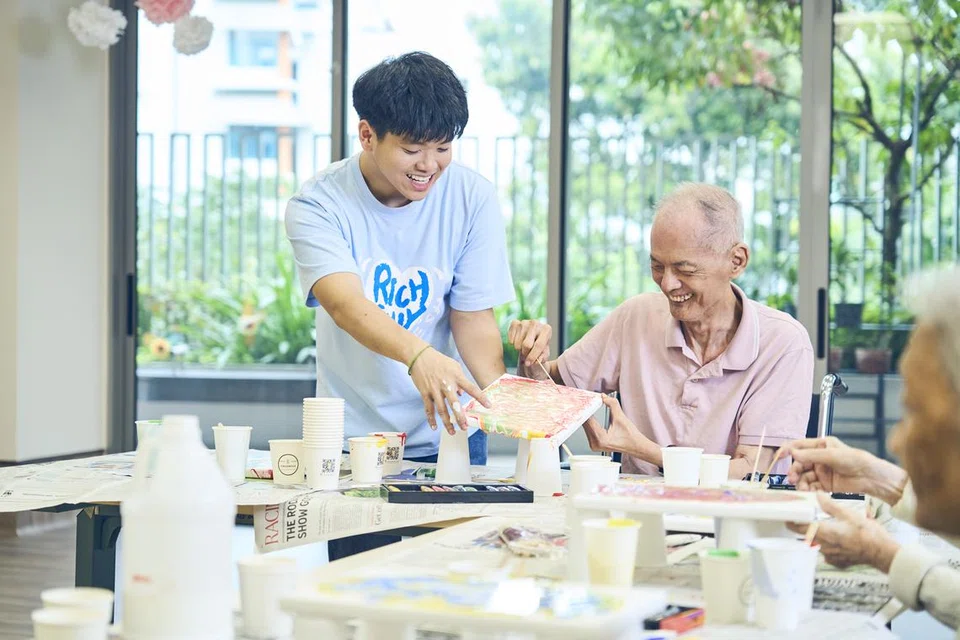 Encik Victor Lee (kanan) meluangkan masa bersama Encik Arthur Leong dalam kegiatan-kegiatan yang dipimpin lelaki muda itu di Rumah Jagaan NTUC Health (Tampines), seperti bengkel lukisan akrilik bersama penduduk.