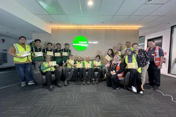 Pengarah Tamar Madinah, Cik Dewi Suhadi (duduk memakai vest keselamatan berwarna oren), menemui kakitangan perkhidmatan bas, Tower Transit Singapura (TTS) untuk mengagihkan kurma kepada mereka. 