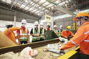 TINJAU OPERASI URUS SISA: Dr Koh Poh Koon (dua dari kiri) dan Encik Zaqy Mohamad (tiga dari kiri) meninjau operasi di loji SembWaste di Tuas. - Foto ZAOBAO