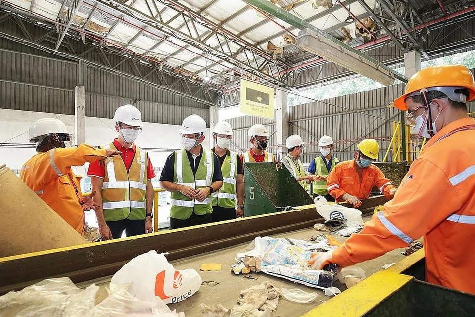TINJAU OPERASI URUS SISA: Dr Koh Poh Koon (dua dari kiri) dan Encik Zaqy Mohamad (tiga dari kiri) meninjau operasi di loji SembWaste di Tuas. - Foto ZAOBAO