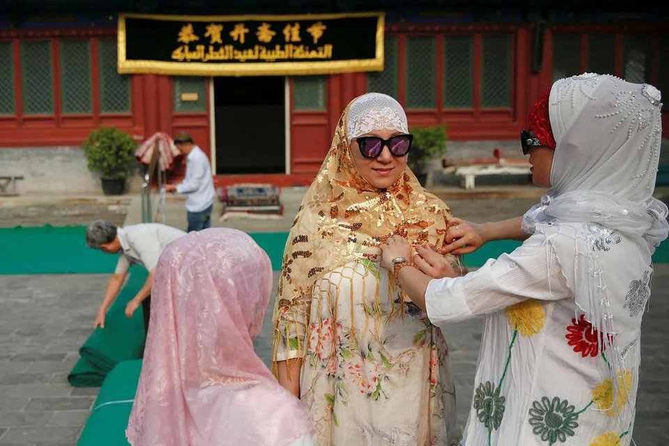 DI BEIJING: Kaum wanita memperkemaskan diri sementara kaum lelaki membentang tikar bersiap untuk solat Raya di masjid bersejarah Niujie di Beijing. - Foto REUTERS
