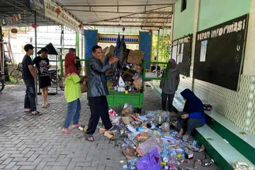 Pentadbir Masjid Al Muharram, Encik Ananto Isworo (tengah), mengeluarkan bahan buangan daripada troli selepas dibawa ke masjid dengan muatan hasil sumbangan penduduk. 