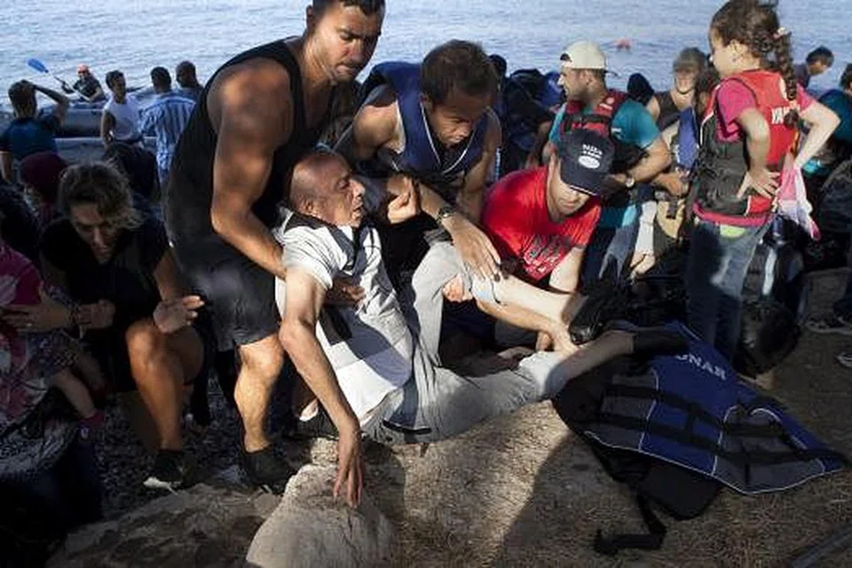 Seorang pelaroan Syria dibantu sejurus tiba dengan dingi di sebuah pulau Greece, Lesbos, pada 8 September. Gambar REUTERS 