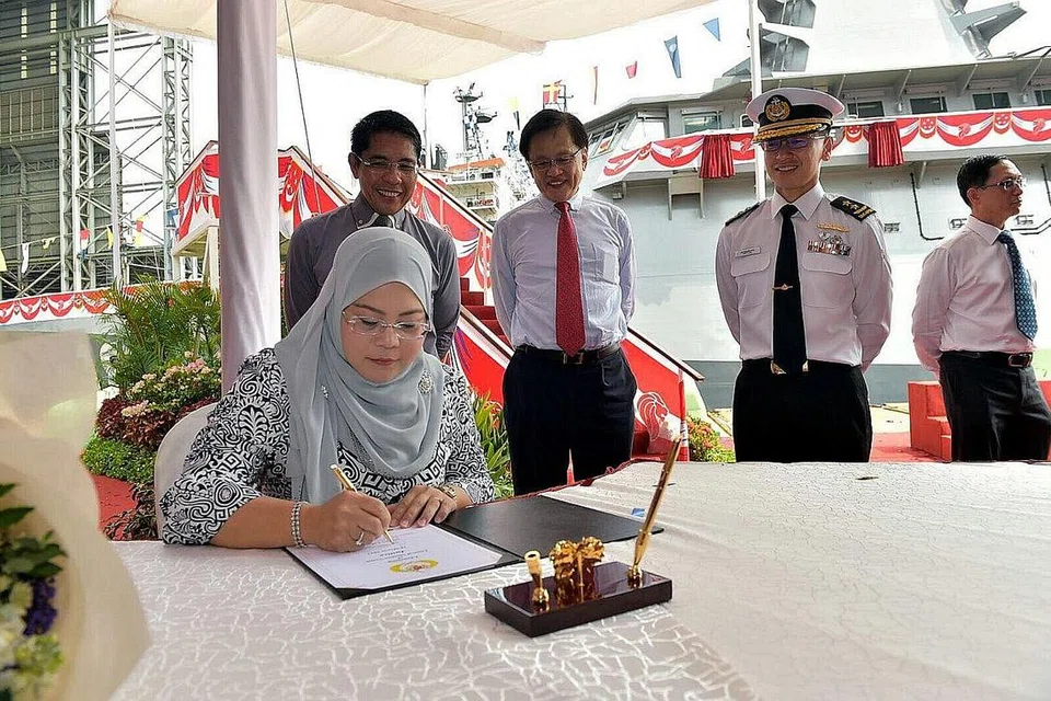 SAAT BERSEJARAH: Cik Sadiah menandatangani dokumen di upacara pelancaran semalam, disaksikan (dari kiri) Dr Maliki; pengerusi ST Marine, Encik Lim Ah Doo dan Laksamana Tentera Laut Lai Chung Han. - Foto MINDEF