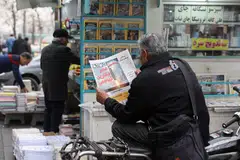 Seorang lelaki membaca akhbar yang memaparkan gambar peluru berpandu Iran sambil duduk di sebelah sebuah kedai buku di Teheran, Iran, pada 7 Februari. 