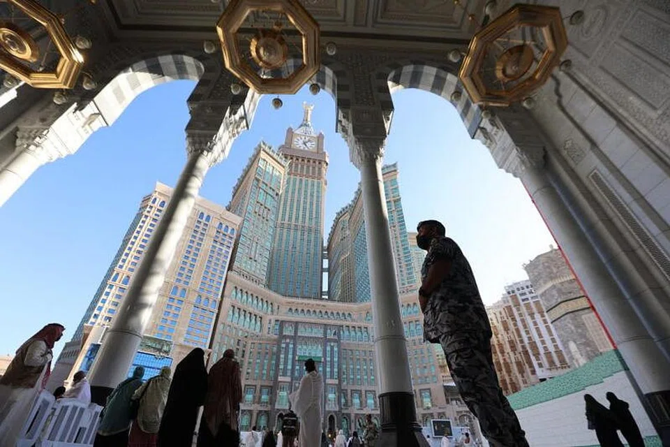 Mecca's Clock Tower is seen in the background as a member of the Saudi security forces stands guard while worshippers pray at the Grand Mosque in the holy city on March 21, 2023. - Poto AFP