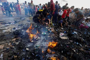 Penduduk Palestin mencari saki-baki makanan ketika menyelongkar puing-puing khemah mereka yang hangus terbakar menyusuli serangan udara tentera Israel di Rafah pada 26 Mei.