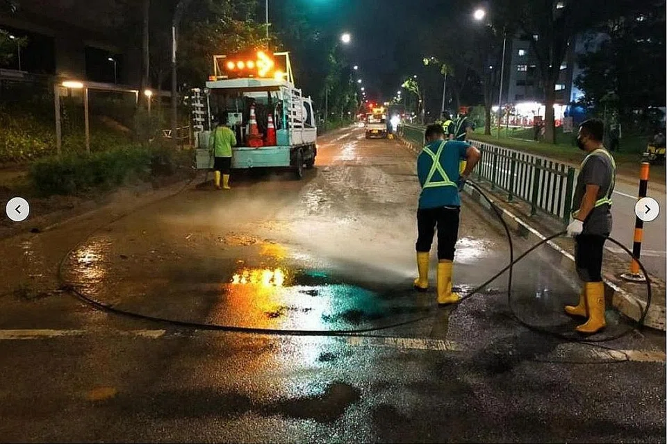 BERSIHKAN KAWASAN: Pekerja kelihatan menjalankan kerja pembersihan setelah air melimpah dari sebuah lereng bukit di Bukit Batok. Kesan limpahan air itu menyebabkan lalulintas terpaksa dialihkan ke laluan alternatif. - Foto FACEBOOK LOW YEN LING